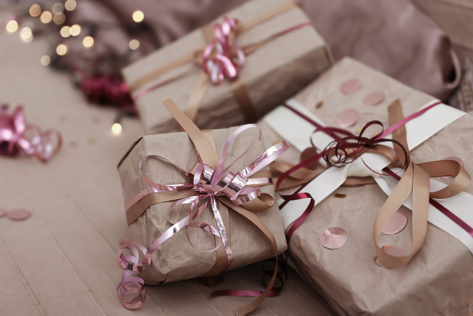 Gift boxes with pink and brown ribbons on a soft surface.